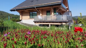 A log cabin with a balcony overlooking a field of clover flowers. - Canadian log cabins in the Hunsrück with lake and national park views (Langweiler)