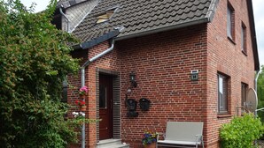 Een bakstenen huis met een pannendak, een huisnummer '38', een bank en plantenbakken.