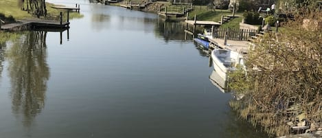 En rolig flod med huse på højre side og en træbro i forgrunden.