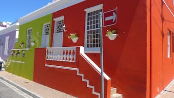 Stunning building with a unique facade, featuring a balcony with potted plants and a striking red arrow sign.