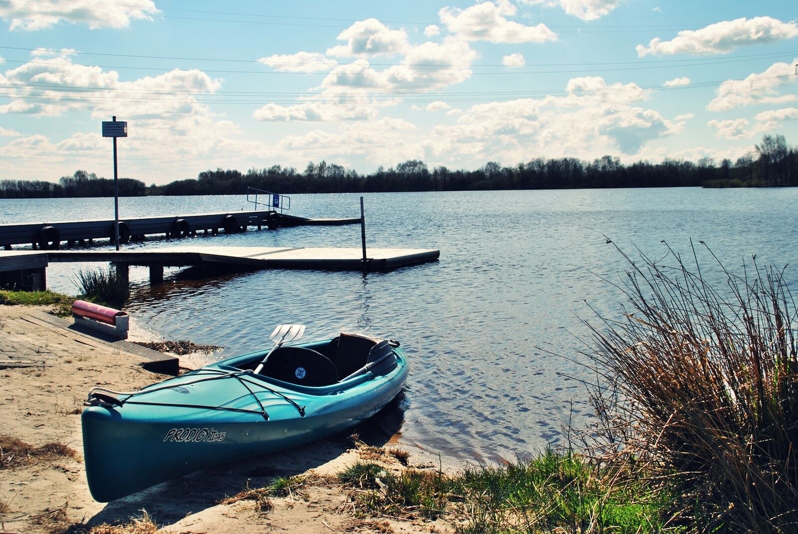 Un lago tranquilo con un muelle y un kayak.