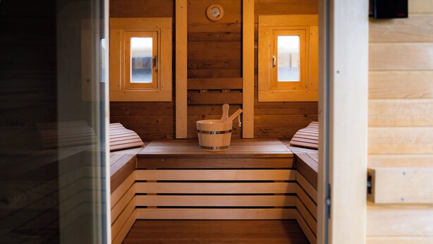 Una sauna con panche in legno, un catino di legno e un orologio appeso al muro.