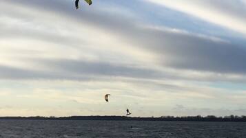 Ein Gewässer mit einem Kitesurfer und einem Schwimmer.