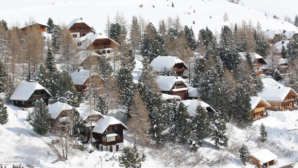 A snow-covered mountain village with log cabins and wooden houses. - Exclusive vacation home in the Nockberge with a sauna and fireplace (Patergassen)