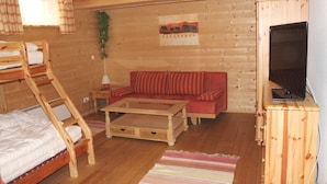 A wooden cabin interior with a bunk bed, a sofa, a coffee table, and a television on a cabinet. - Exclusive vacation home in the Nockberge with a sauna and fireplace (Patergassen)
