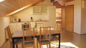Un comedor con mesa y sillas de madera, una cocina con fregadero y armarios, y un techo de madera.