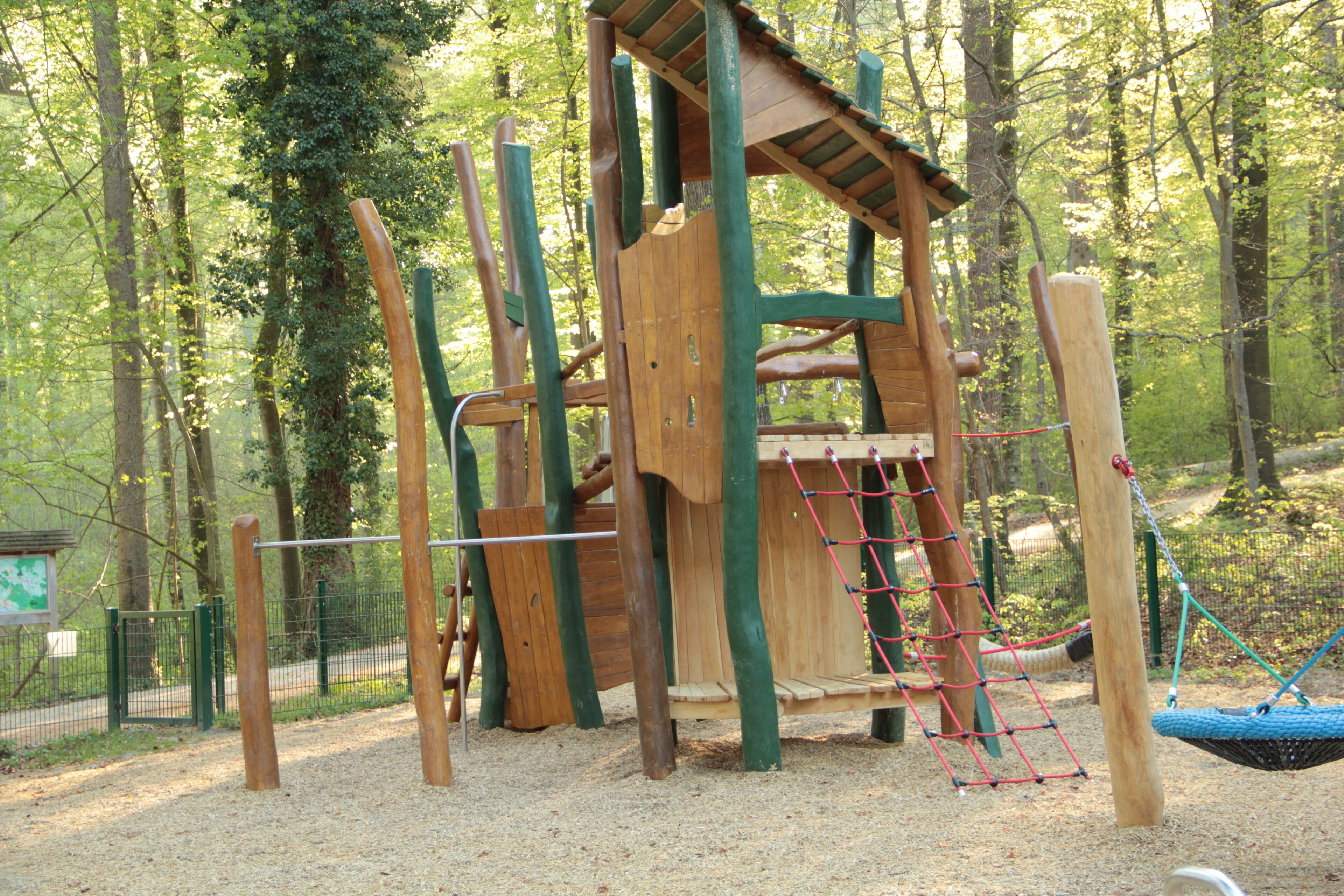 Eine Spielkonstruktion aus Holz in einem bewaldeten Park.