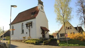 Una iglesia blanca con una torre de reloj, una campana y un campanario pequeño.