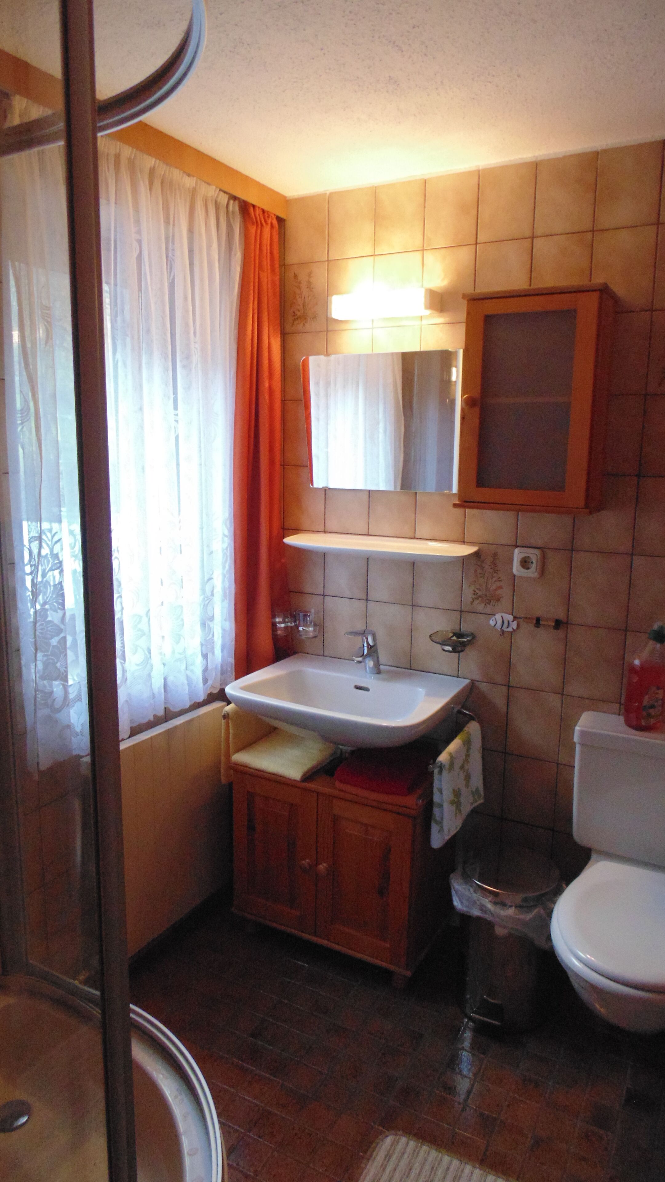 A bathroom with a sink, mirror, toilet, and shower area.