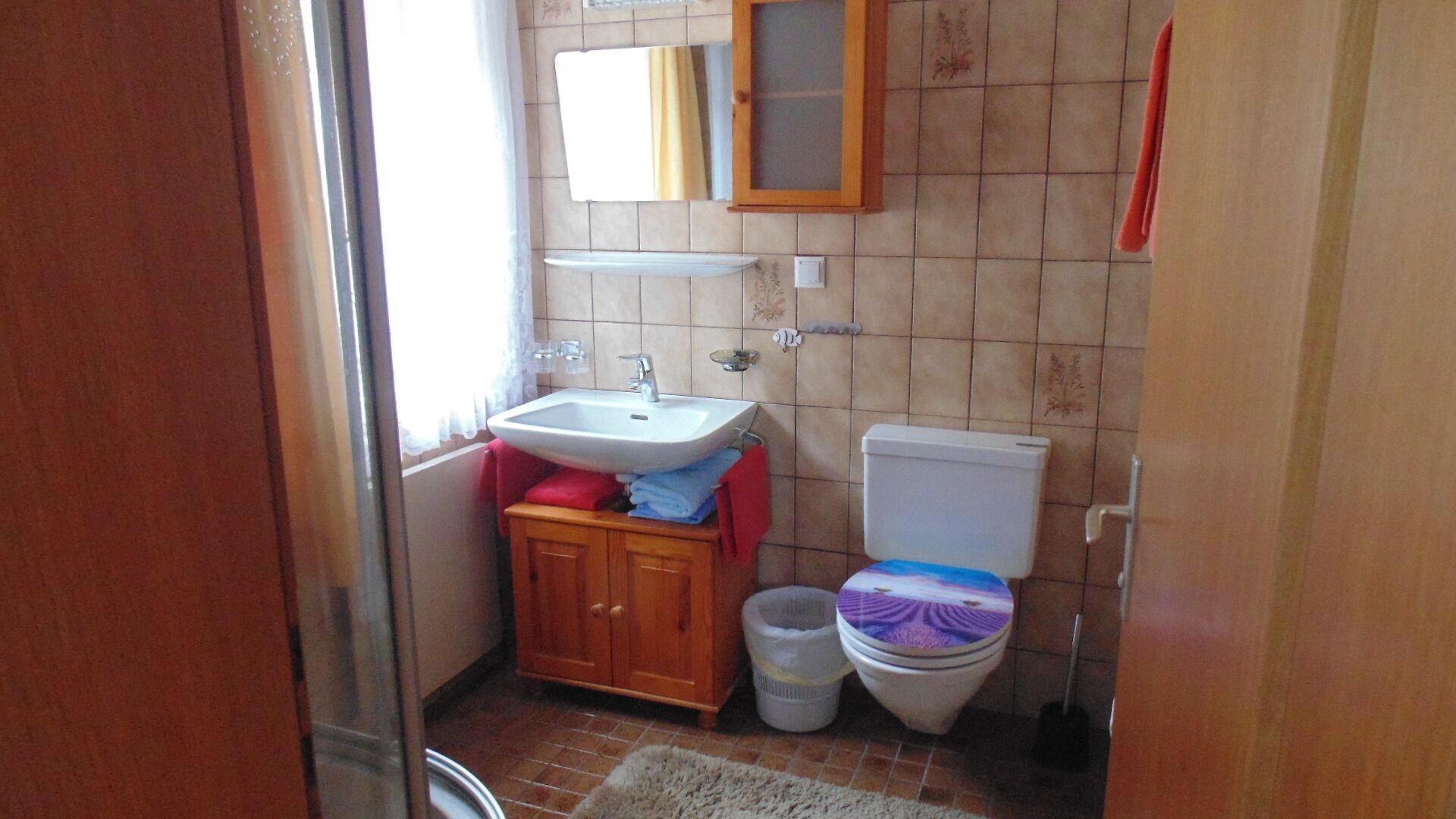 A small bathroom with a sink, toilet, and cabinet.