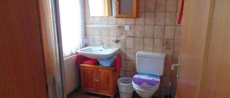 A small bathroom with a sink, toilet, and cabinet.