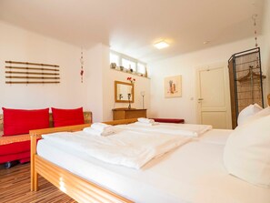 A hotel room with a large bed, a wooden headboard, a red sofa, a dresser, a mirror, and a door with a metal gate.