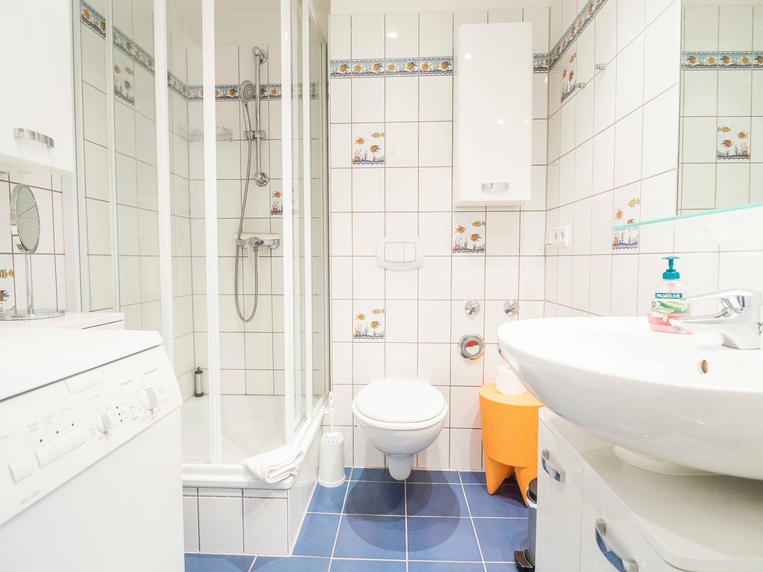 Een badkamer met douche, toilet en wastafel.
