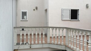 A building with a white exterior, a balcony with white balustrades, and a small window.