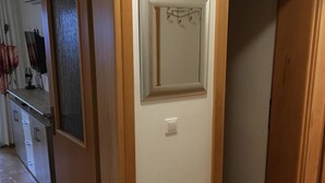 A hallway with wooden doors, a mirror, and a light switch on the wall.