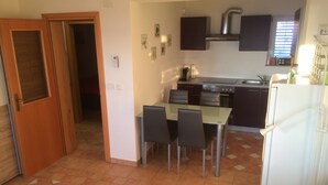 A compact kitchen with a dining table and chairs, a refrigerator, and a stove.