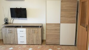 A kitchen with a wooden cabinet, a TV mounted on the wall, and a refrigerator.