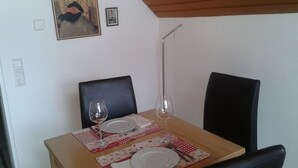 Ein Esstisch ist gedeckt mit Tellern, Besteck und Weingläsern, darüber an der Wand hängt ein Gemälde und ein kleines gerahmtes Bild.