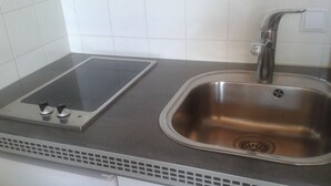 Eine Küche mit Spüle aus Edelstahl, integriertem Kochfeld und weiß gefliestem Fliesenspiegel.