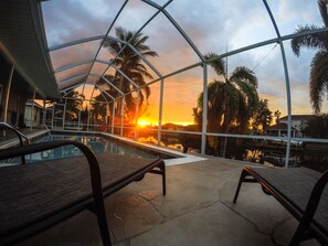 A pool area with a glass ceiling, lounge chairs, and a sunset view. - Dream villa on the canal with southern exposure in a quiet residential area, direct golf access (Cape Coral)