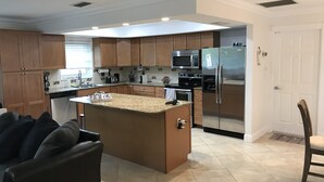 A modern kitchen with wooden cabinets, a stainless steel refrigerator, a microwave, and a coffee maker.