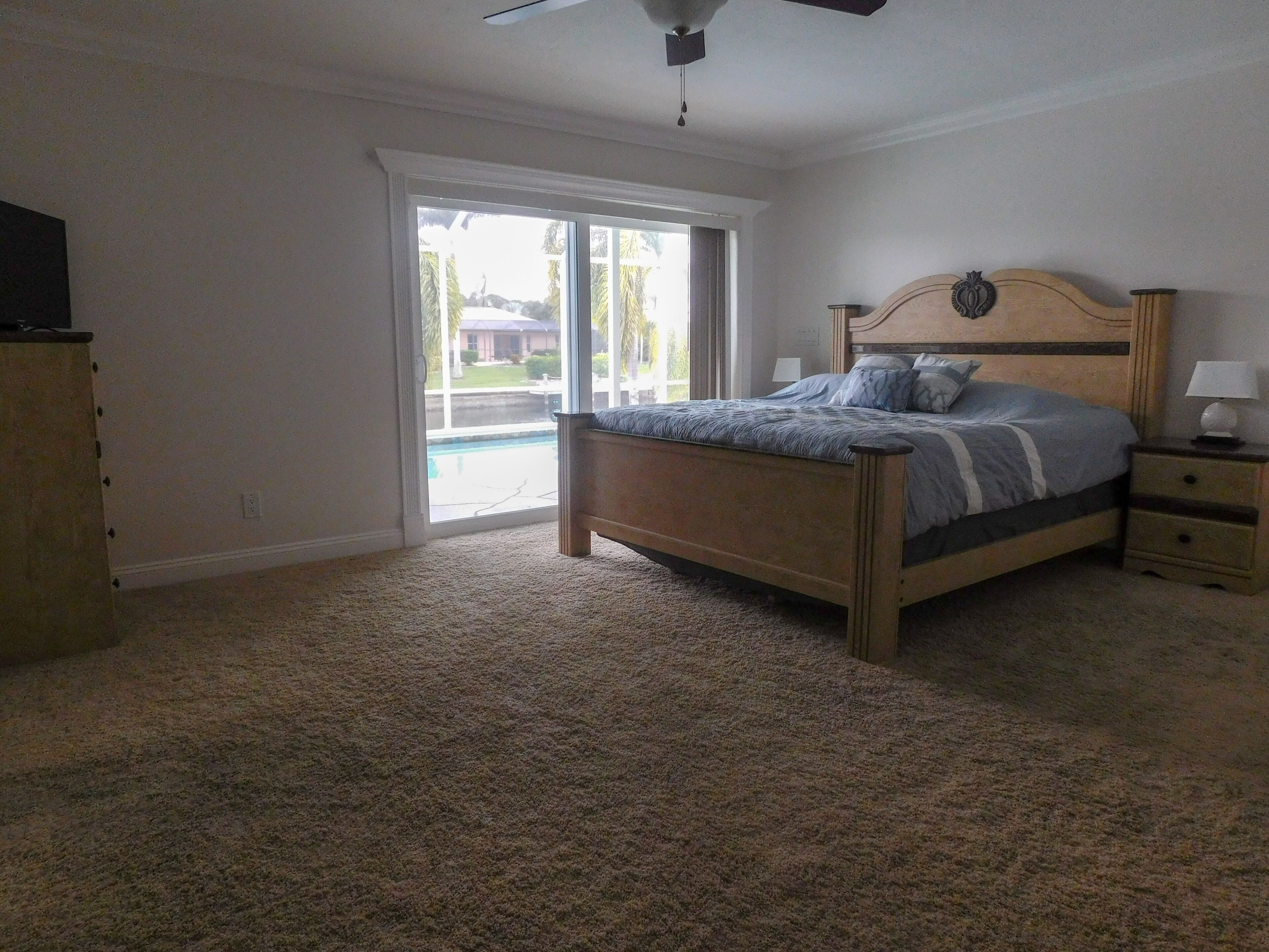Een slaapkamer met een bed, een nachtkastje, een dressoir en een schuifdeur naar een terras.
