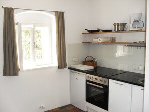 Compact kitchen with a modern design, featuring a black countertop, white cabinetry, and essential appliances.