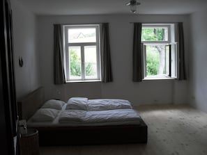 Enjoy a peaceful retreat with a single bed positioned against the wall, offering views of lush greenery through two windows.