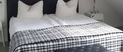 Une chambre à coucher avec un lit, un banc et une table de chevet.