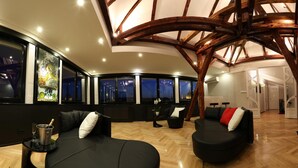 A modern interior with a curved ceiling, black sofas, and a wooden floor.