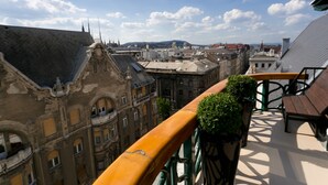 A balcony with a view of historic buildings and a distant mountain range.