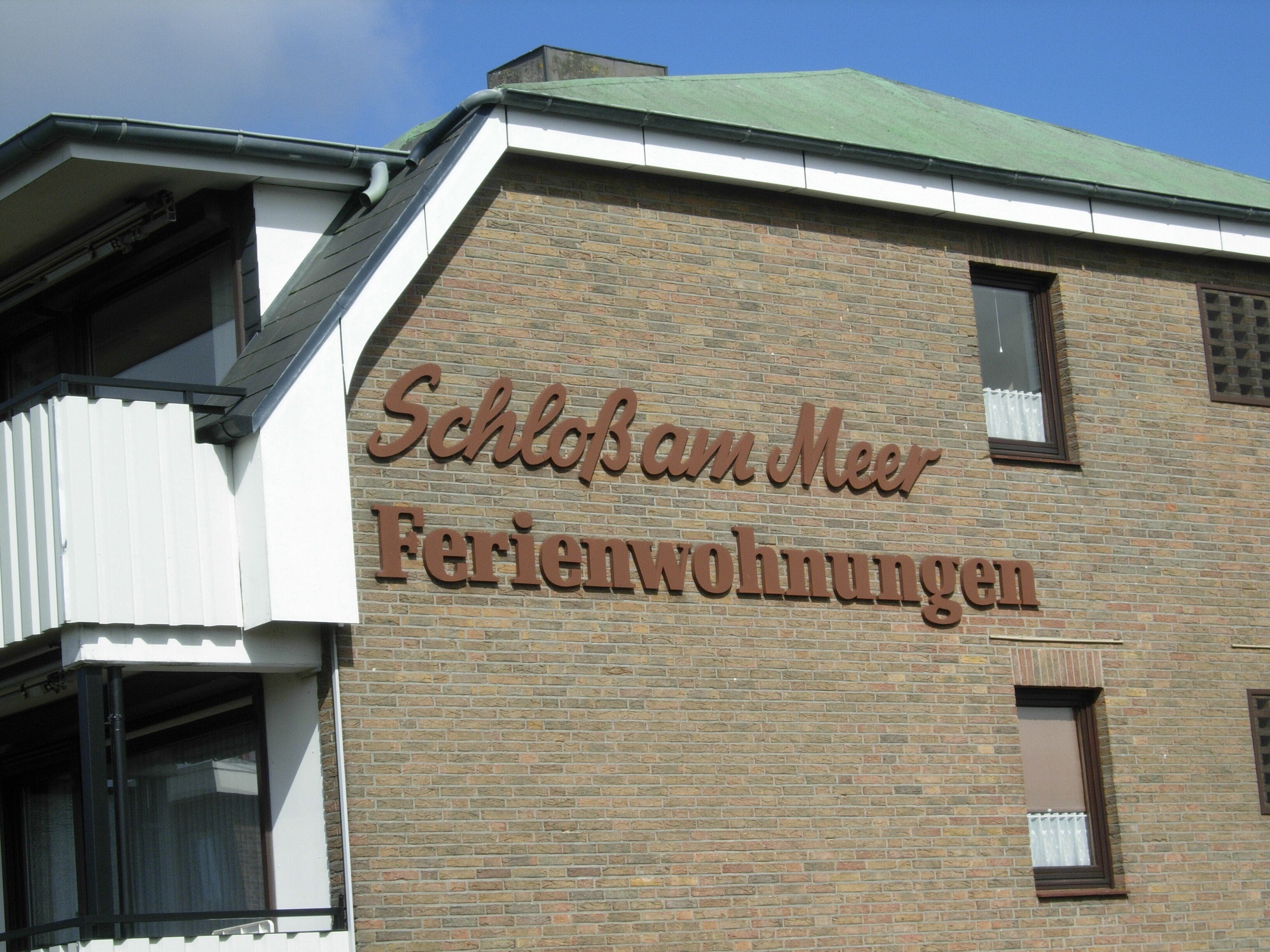 A building with a sign reading "Schloßan Meer Ferienwohnungen".