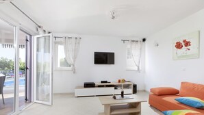 A modern living room with a sofa, a coffee table, and a TV on a white wall. - Villa Mirta * private pool, terrace with sea view, free WiFi, 1 km to the sea (Crni)