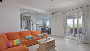 A living room with an orange sofa, a wooden coffee table, and a view of a balcony with outdoor furniture. - Villa Mirta * private pool, terrace with sea view, free WiFi, 1 km to the sea (Crni)