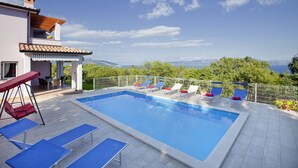 A swimming pool with lounge chairs and a table, surrounded by a fence, with a view of the landscape. - Villa Mirta * private pool, terrace with sea view, free WiFi, 1 km to the sea (Crni)