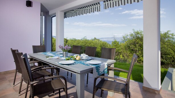 An outdoor dining area with a table set for four, surrounded by wicker chairs, overlooking a lush landscape. - Villa Mirta * private pool, terrace with sea view, free WiFi, 1 km to the sea (Crni)