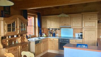 Une cuisine de style rustique, avec des meubles en bois, un évier, une cuisinière et un coin repas comprenant une chaise.