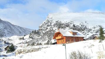 Eine Holzhütte mit geneigtem Dach, gelegen an einem mit Schnee bedeckten Hang.
