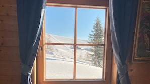 Acogedor cuarto de cabaña con un ventanal grande que ofrece vistas a un paisaje nevado.