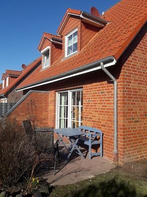 Une maison avec une façade en briques rouges, un toit en tuiles et une fenêtre à cadre blanc.