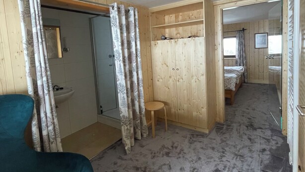 Une pièce avec une chaise bleue, une armoire en bois et une petite table.