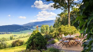 Une terrasse avec une table et des chaises donnant sur un paysage pittoresque.