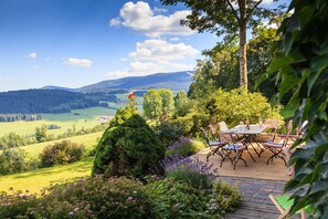 Een terras met een tafel en stoelen met uitzicht op een schilderachtig landschap.
