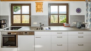 Une cuisine moderne équipée d’un four Bosch, d’un lave-vaisselle encastré et d’une grande fenêtre donnant sur l’extérieur.