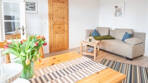 A living room with a wooden door, a sofa with cushions, a coffee table, and a striped rug.