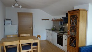 Une cuisine de taille réduite avec des meubles en bois, une table à manger avec des chaises et un four encastré.