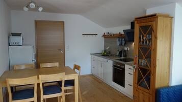 Eine kompakte Küche mit Holzausstattung, einem Esstisch mit Stühlen und einem eingebauten Backofen.