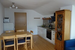 Eine kompakte Küche mit Holzausstattung, einem Esstisch mit Stühlen und einem eingebauten Backofen.