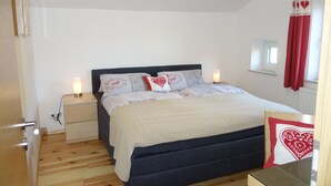 Une chambre à coucher avec un lit, des tables de chevet et une fenêtre avec des rideaux.