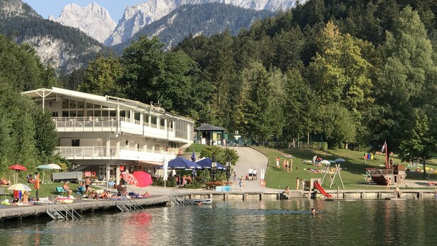 Un hôtel situé au bord d’un lac, doté d’une piscine, d’un espace extérieur aménagé et offrant une vue sur les montagnes.